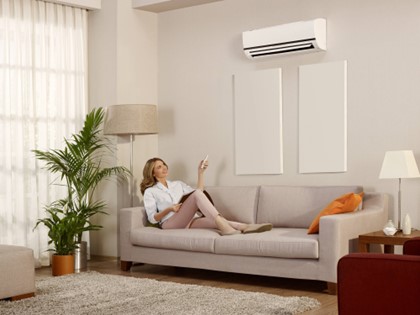 A person sitting on a couch operating the air conditioner